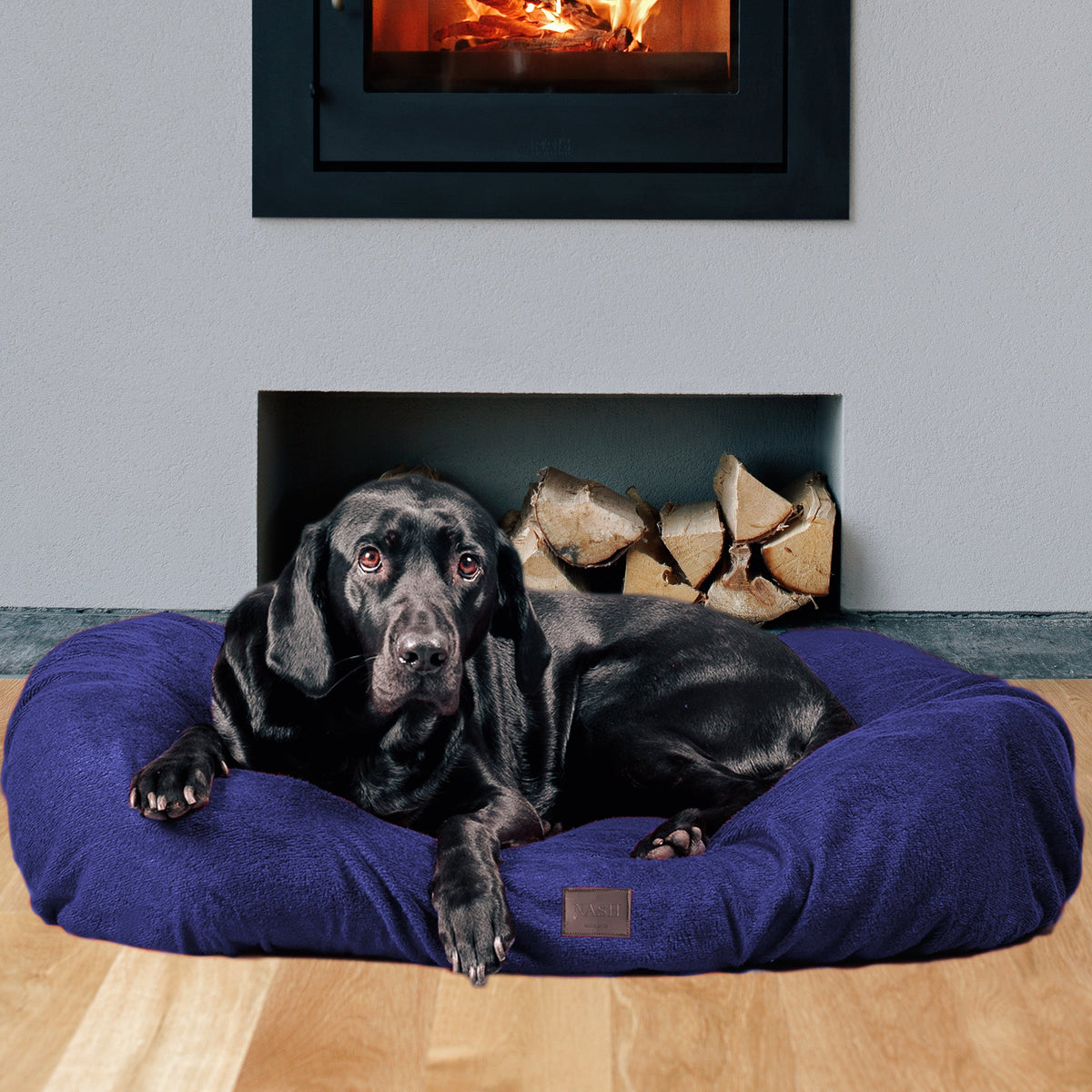 Labrador relaxing in front of the fire on its bed. The bed is protected with the NASH bamboo dog bed cover in navy blue.