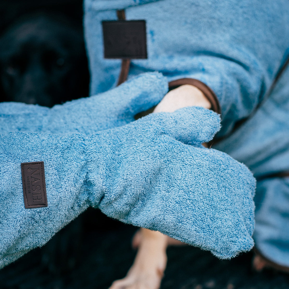 Golden Labrador in the NASH dog drying coat, having its paws dried using the matching Cambridge blue dog drying mitts, also by NASH.