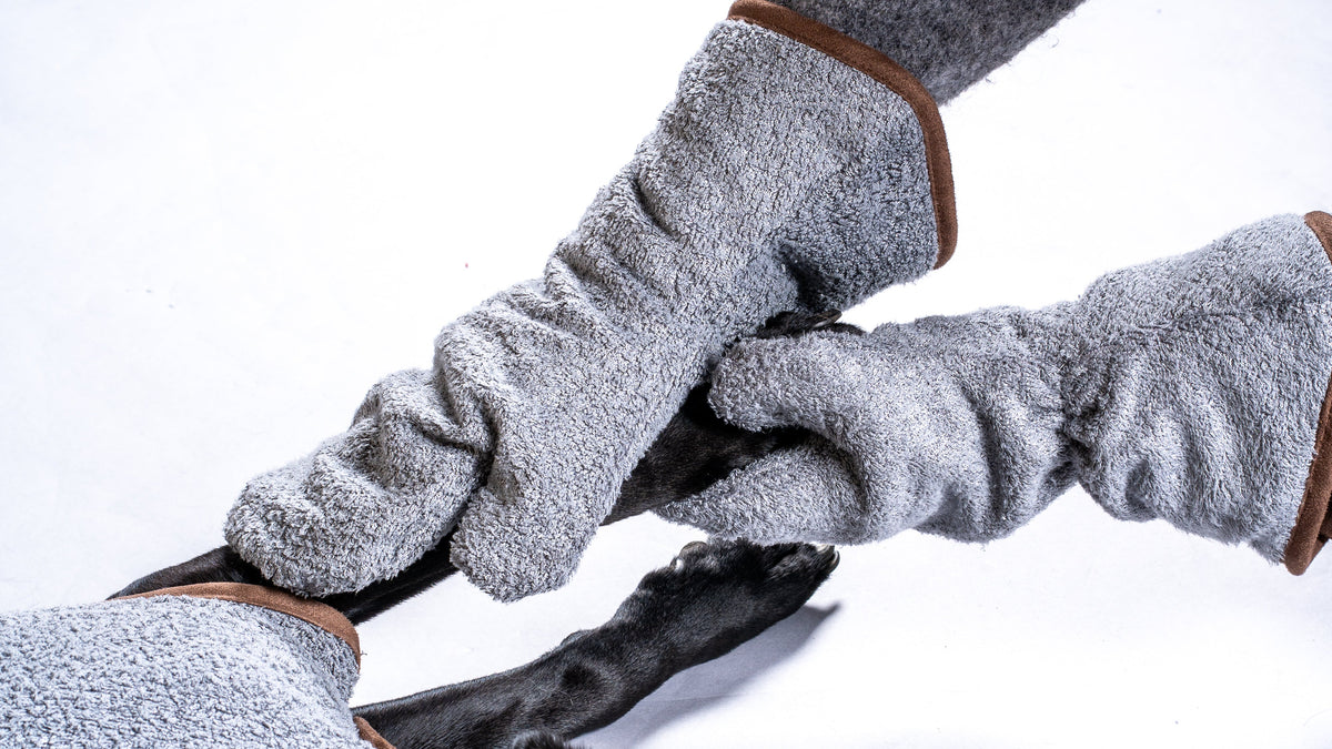 NASH bamboo dog drying mitts in grey, being used to dry off a black Labrador's paws.