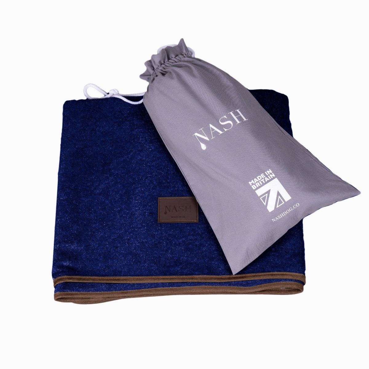 Folded NASH bamboo dog throw in navy blue, with its reusable bag placed on top.